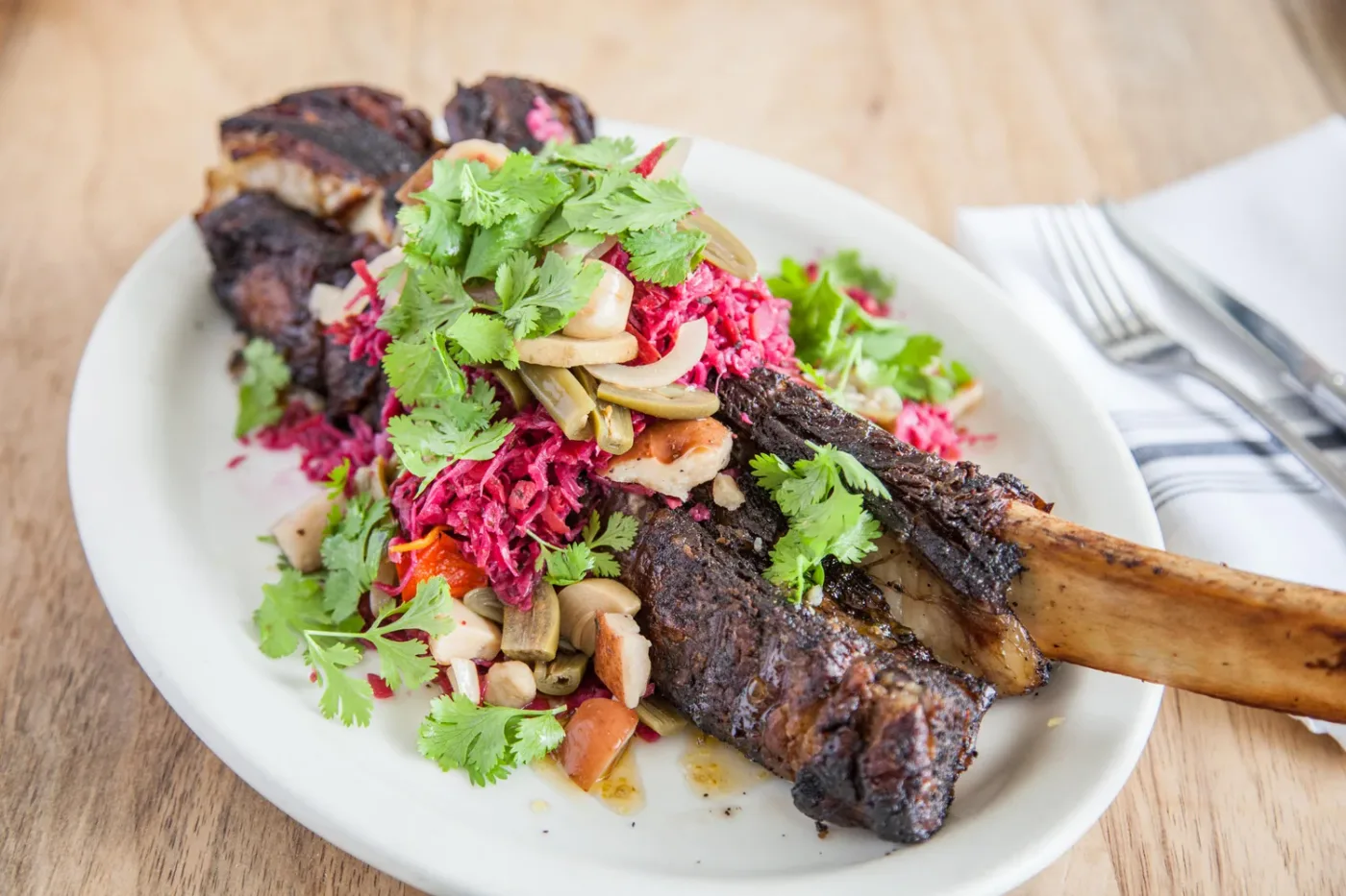 A bone-in meat dish with greens at Dai Due