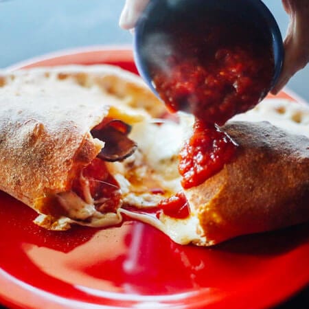 A calzone topped with tomato sauce at Home Slice Pizza