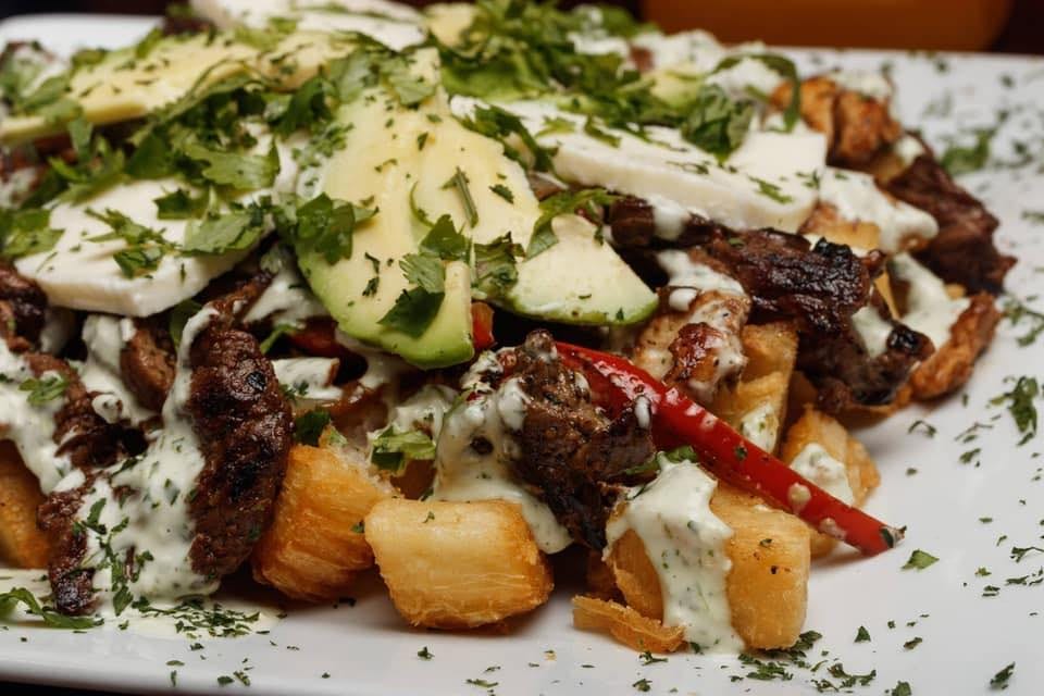 Grilled meat with avocado, cheese, herbs and yucca. Arepitas.