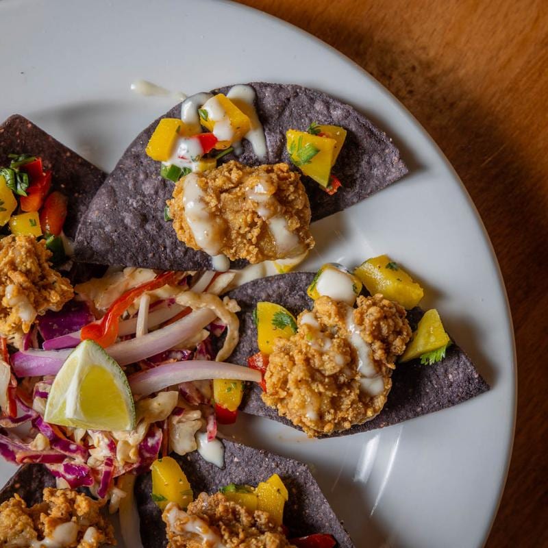Crisp blue corn food with toppings on a white plate. Blue Corn Harvest.