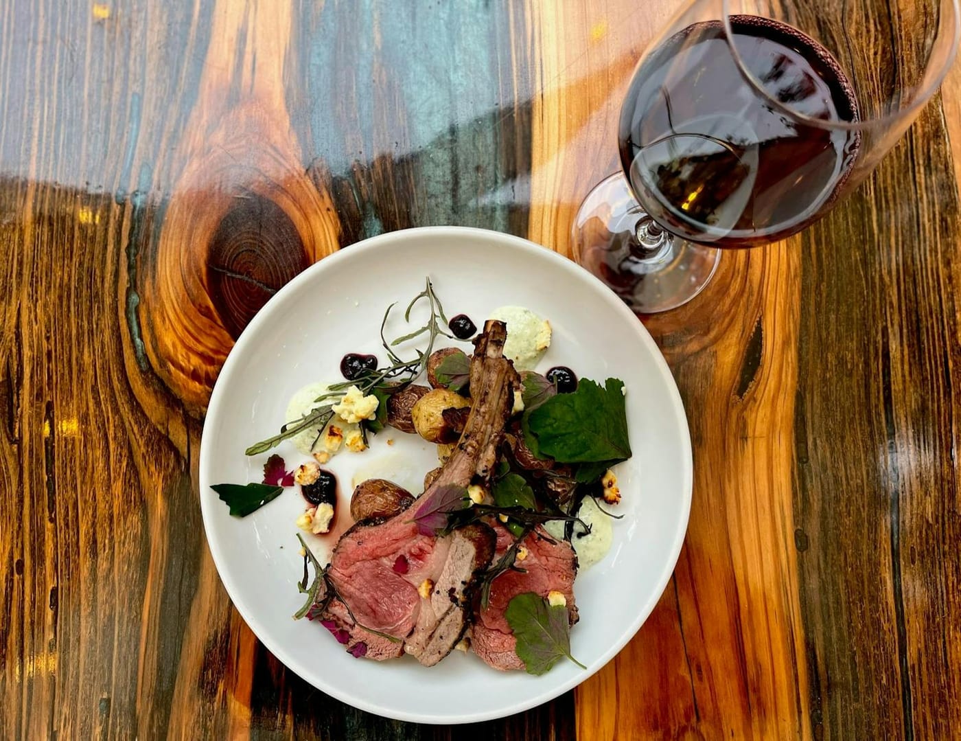 Plated sliced meat, roasted vegetables and wine. Store House Market & Eatery.