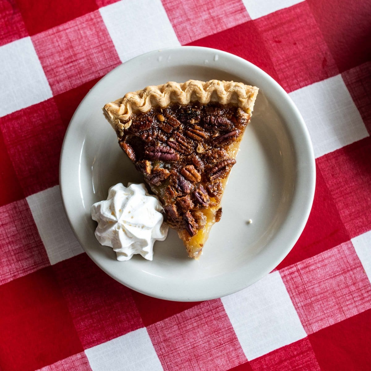 Slice of pecan pie on a checkered table cover. Texan Cafe & Pie Shop.